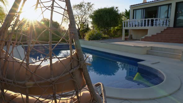 Luxurious Hanging Rocking Chair Next to the Clean Pool and Villa Residence