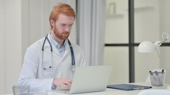 Redhead Male Doctor Working on Laptop 