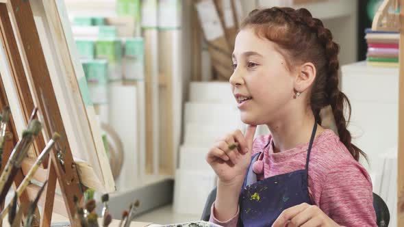 Cute Little Girl Showing Thumbs Up While Painting a Picture at the Art Class