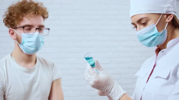 Young Man Waiting for Injection Near Nurse