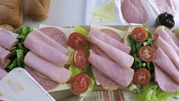 Time-lapse. Step by step. Preparing fresh sub sandwich on white and wheat hoagies.