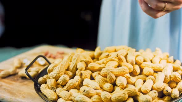 The Woman Analyzes the Quality of Peanuts with Bark