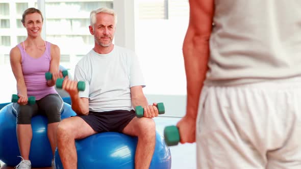 Exercise Class Sitting on Exercise Balls Lifting Hand Weights