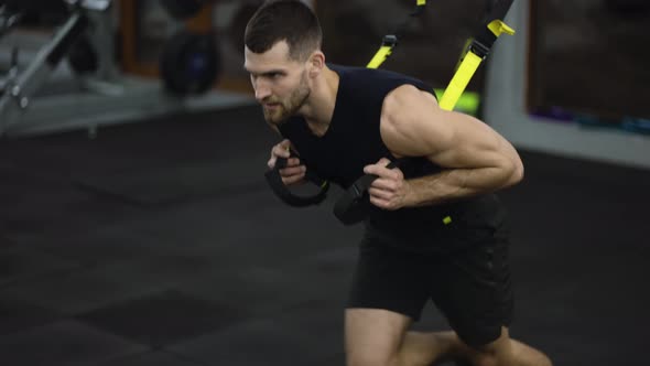 Sportsman Doing Confrontation Running Exercise with TRX Straps at Gym