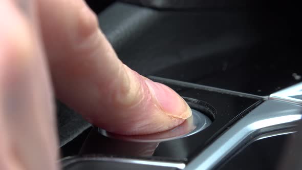 A woman presses a Start-Stop Engine button in a car - closeup