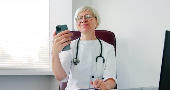 Woman doctor consulting patient using phone video call distant. Medical worker talking to client