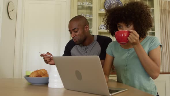 Happy mixed race couple eating breakfast in their kitchen