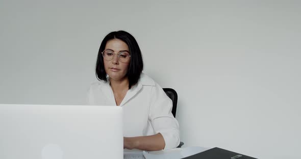 Female Lecturer in Glasses Chatting on a Laptop During Remote Learning in Office