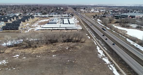 Highway parallel flight showing affordable housing car dealership and empty space drone shot 4k