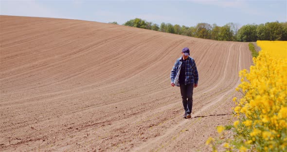 Agriculture - Farmer or Agronomist Walking on Field Looking at Crops.