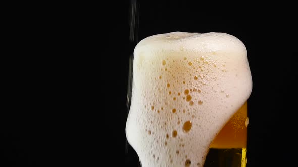 Close up pouring lager beer in glass over black
