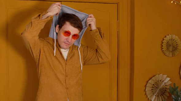 Young Man in Bright Glasses Preening Himself in Front of Camera