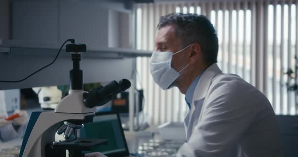 Scientist Studying Sample in Microscope