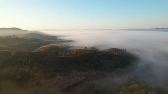 4K aerial view over mountain at sunrise in heavy fog. golden morning sunlight