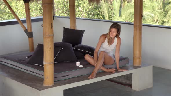 Young Woman Applying Body Lotion in Tropical Patio