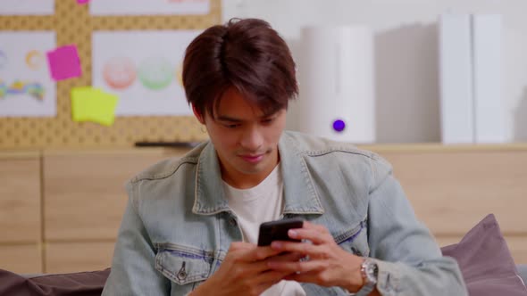 Asian man is smiling and expressing his happy feeling on the cellphone screen