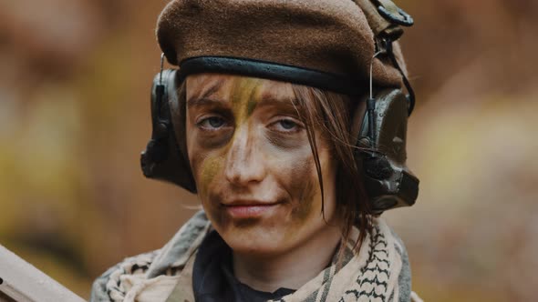 Portrait of an Confident Female Soldier with Headphones and Face Paint Camouflage