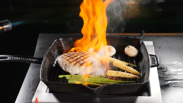 Professional Chef Cooking Flambe Style Dish on Restaurant Kitchen