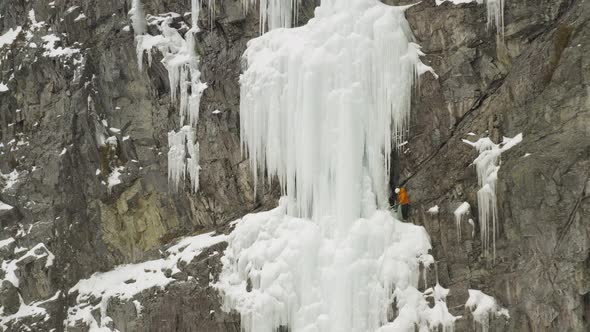 Extreme climbers on frozen cliff face Aerial reveal 4K