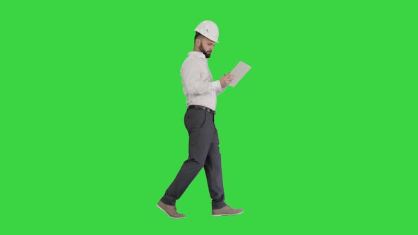 Construction Specialist Using a Tablet Computer While Walking on a Green Screen, Chroma Key.