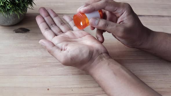 Rear View of Man's Hand with Medicine Spilled Out of the Pill Container