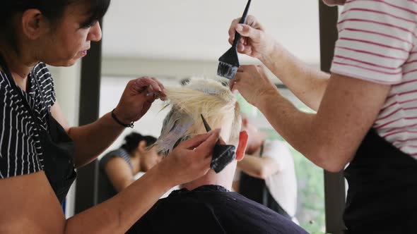 Rear view woman having her hair styled by hairdressers