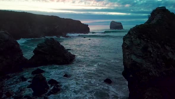 Flying near huge ocean rocks close to crashing waves into the setting sun at Sand Dollar Beach in Bi