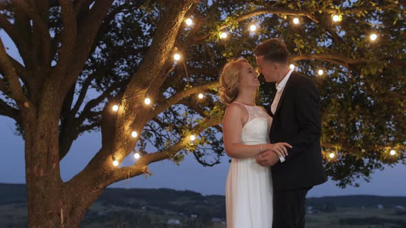 Groom tenderly embraces and kisses his bride alt