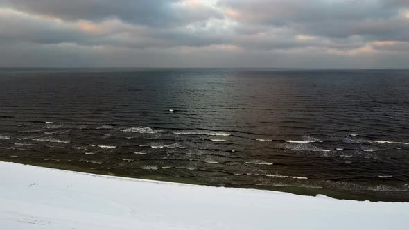 Waves of the winter sea roll over the snow towards the shore