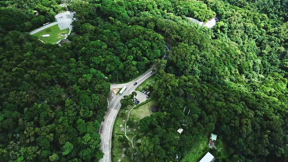 A dynamic tracking aerial shot of a travelling bus on the winding roads of the Tai Mo Shan mountains