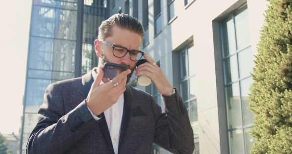 businessman in glasses and formal clothes talking on smartphone while walking