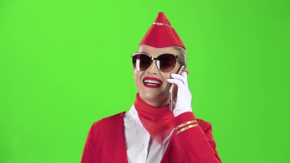 Stewardess in Sunglasses in a Red Suit Speaks on the Phone, Green Screen, Slow Motion