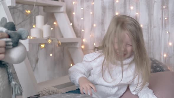 Child with Long Blond Hair Plays with Winter Themed Toys