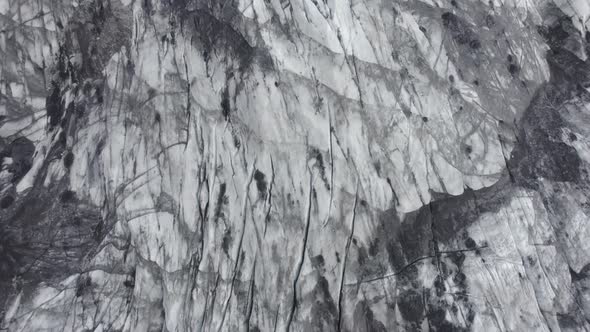 Aerial view above a ashy, darkened glacier surface, in Iceland - birds eye, drone shot