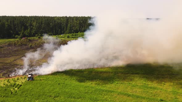 Puffs of Thick Gray Smoke and Fire Spread Across a Large Field