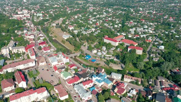 Aerial View of a Township in a Valley Among Green Trees on a Summer Sunny Day