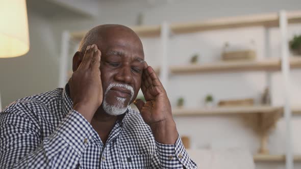 Upset Senior African American Man Suffering From Headache Attack Massaging His Temples at Home