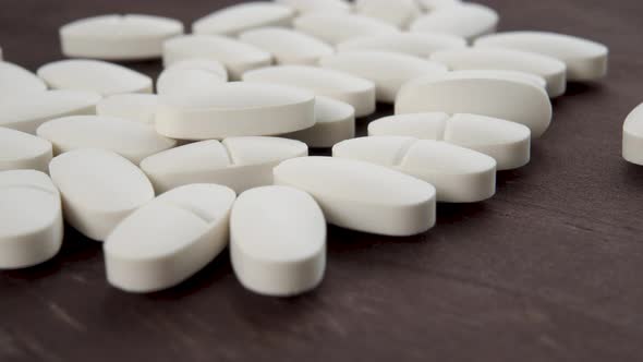 White oval medical pills on a wooden brown background