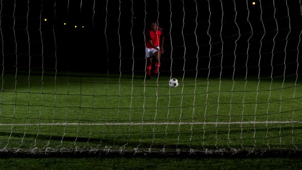 Soccer player scoring a goal against open goal post