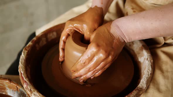 Close Up Footage of a Woman Sitting at Pottery Wheel in Ceramics Studio Shaping Clay Vase Diving