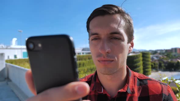 Young Man Scrolling Smartphone Screen