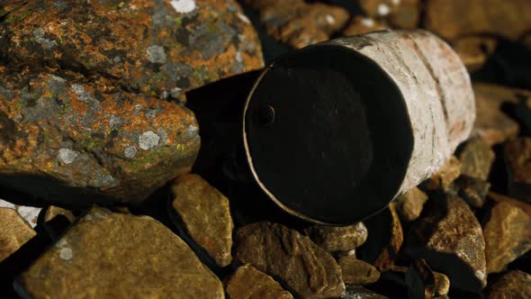 Rusty Destroyed Metal Barrel on Beach Rocks