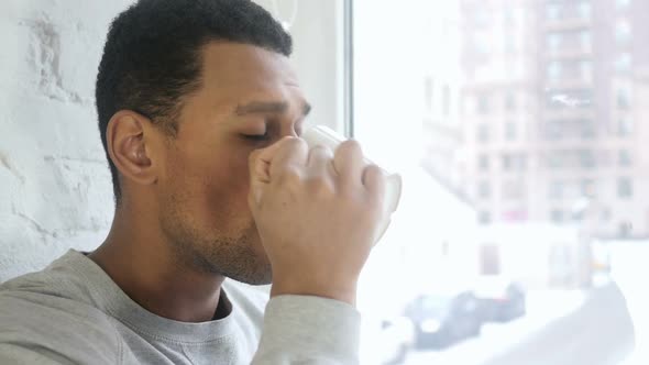 Close Up of AfroAmerican Man Drinking Coffee Looking Through Window