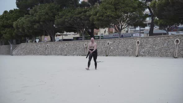 Shirtless Man Smiles At The Camera While Untangling Kite Lines At The Beach