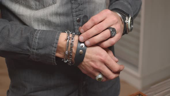 Closeup of Biker Hands Motorcyclist with Signet Rings Put on Leather and Metal Bracelets Getting