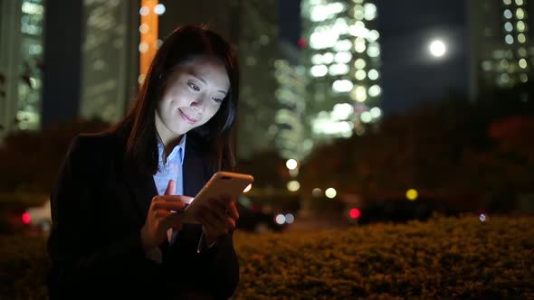 Business woman sending sms on cellphone at night, mobile office concept