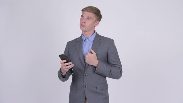 Happy Young Handsome Businessman Thinking While Using Phone