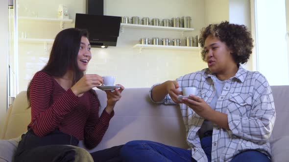 Two Girlfriends Gossiping While Sitting on the Couch