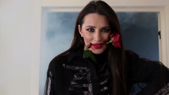 Beautiful Brunette with Stylish Makeup with Blood and Rose in Her Mouth