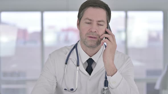 Portrait of Middle Aged Doctor Talking on Smartphone in Office 